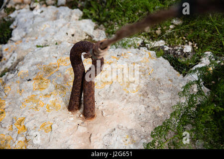 Rostiges Metall Kabel gebunden an eine Metallöse in den Boden Closeup verwischt. Stockfoto