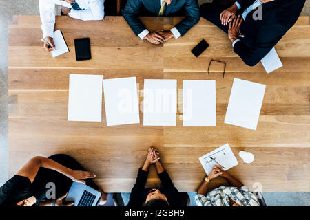 Draufsicht der Büroangestellte sitzen um einen Tisch im Konferenzraum. Multi-ethnischen Geschäftsleute in Treffen mit Leerseiten am Tisch. Stockfoto