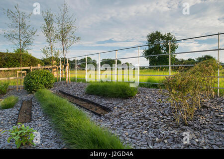 Schönen gepflegten, privaten Garten (zeitgenössisches Design, Sträucher & Gräser in Linien auf erhöhte Grenze) angrenzende Landschaft - Yorkshire, England, UK. Stockfoto