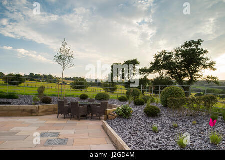 Schöne, Private, zeitgenössische gestalteten, Garten, England, GB, UK - Lieferservice (Patio-Möbel) angehoben, Grenzen, Gräser & topiary Sträuche. Stockfoto