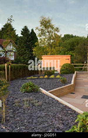 Schönen, privaten Garten, Yorkshire, England, UK - stilvolles, modernes Design, harte Landschaftsbau (Pflaster) Schuppen & neue Pflanzen auf Holz Hochbeete. Stockfoto