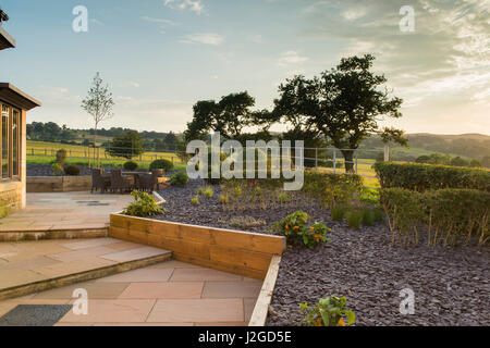 Schöne, private, zeitgenössisch gestalteten, Garten, England, GB, UK - Sitzmöbel (Terrasse) ebnete Aussentreppe, erhöhte Grenzen & topiary Sträuche. Stockfoto