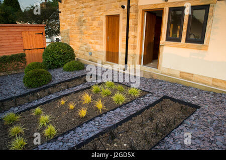 Schönen, privaten Garten, England, GB, UK. Stilvolles, modernes Design, Landschaftsbau, Neuanpflanzungen (Gräser) versunkene Betten, Schiefer Mulch, Formschnitt & Schuppen Stockfoto