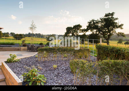 Schöne, Private, zeitgenössische angelegten, Garten, England, GB, UK - Pflaster (Gartenmöbel), erhöhte Grenzen & Formschnitt Sträucher Sitzgelegenheiten im Freien. Stockfoto