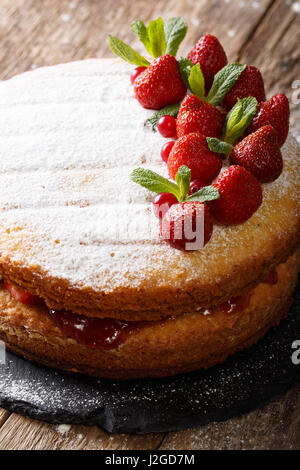 Victoria Sandwich Kuchen mit Erdbeeren und Minze Closeup auf dem Tisch dekoriert. vertikale Stockfoto