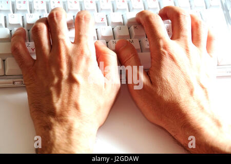 männliche Hände auf einer weißen Tastatur tippen Stockfoto