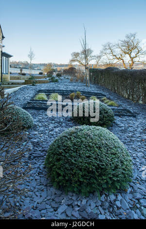 Winter frostig Blick auf privaten Garten mit stilvollem, zeitgenössischem Design, schwer Landschaftsbau und Pflanzen auf ausgelöst Betten - Yorkshire, England, UK. Stockfoto