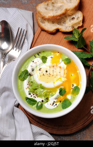 Püree Erbsensuppe mit pochiertem Ei, saure Sahne, Minze Blätter mit Gewürzen gewürzt. Stockfoto