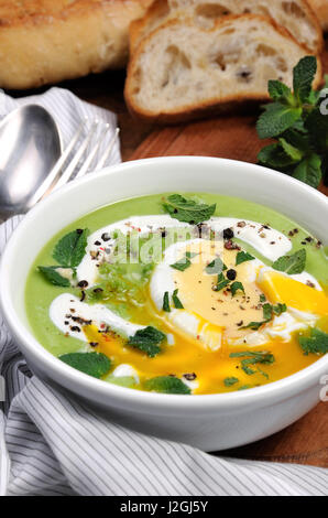 Püree Erbsensuppe mit pochiertem Ei, saure Sahne, Minze Blätter mit Gewürzen gewürzt. Stockfoto