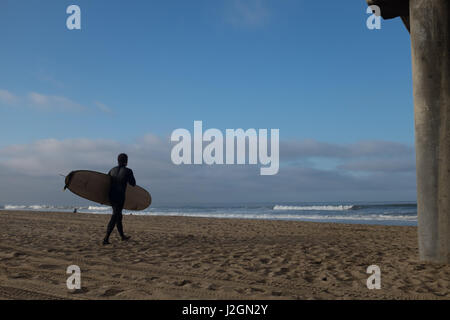 Ein einsamer Surfer am Strand kurz nach Sonnenaufgang am Huntington Beach, Kalifornien Stockfoto