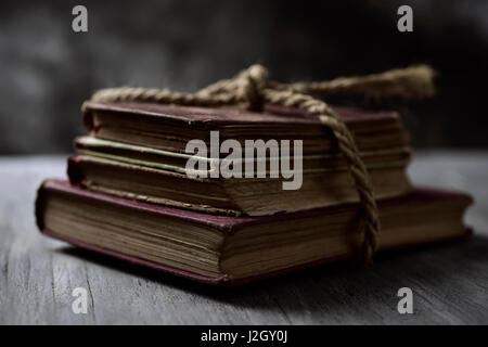 ein Haufen alter Bücher gebunden mit eine Jute string auf einem rustikalen Holztisch Stockfoto