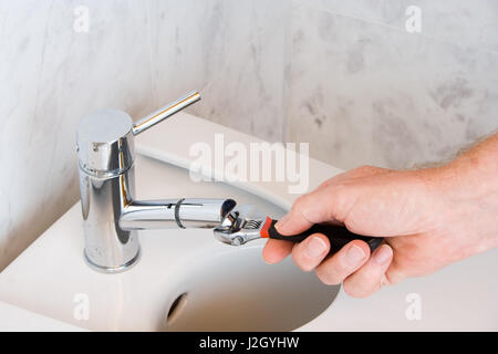 Klempner reparieren einen Wasserhahn im Badezimmer Stockfoto