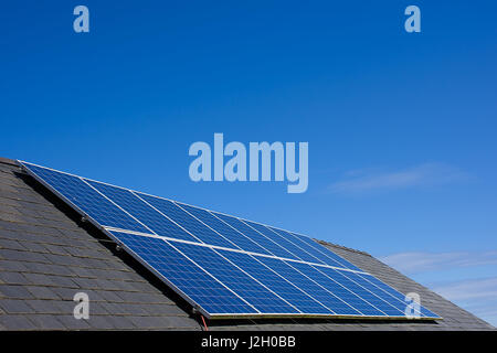 Sonnenkollektoren auf Haus Dach mit blauen Himmel im Hintergrund, North Wales, UK. Solarenergie, erneuerbare Energie, umweltfreundliche Energieerzeugung, UK. Stockfoto