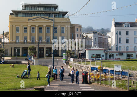 Das alte Kino Riviera in Teignmouth, Devon, UK mit Menschen, die zu Fuß in Richtung Meer, vorbei an der Bowling Green und alte Informationsbüro. Stockfoto