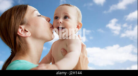 glückliche Mutter küssen Baby über blauen Himmel Stockfoto