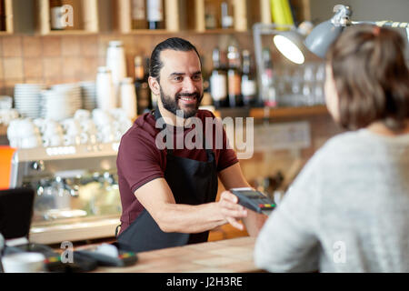 Mann oder Kellner mit Kartenleser und Kunden in Bar Stockfoto