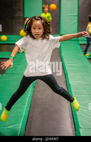 Ein fröhliches vietnamesisches amerikanischen Mädchen springt auf das Völkerball Gericht eines indoor Trampolin Parks in Costa Mesa, CA. Stockfoto