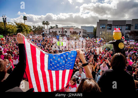 Eine amerikanische Flagge ist entfaltet vor der Menge auf den Januar 2017, Anti-Trump Frauen März in Santa Ana, CA. Hinweis Donald Trump Bildnis auf der rechten Seite. Stockfoto