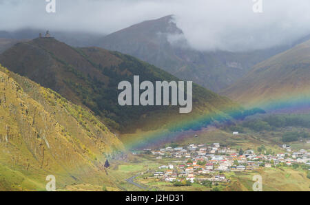 Regenbogen über dem georgischen Dorf Stepantsminda nach dem Regen im september Stockfoto