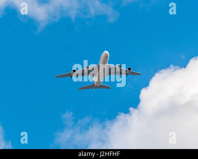 Jet-Passagierflugzeug gegen blauen Himmel mit Wolken von unten gesehen. Stockfoto