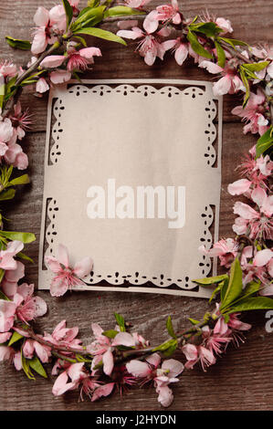 Kranz der Pfirsichbaum Blumen auf einem Holztisch Hintergrund, Retro-Stil-Foto mit dem Schreiben von Karte Stockfoto