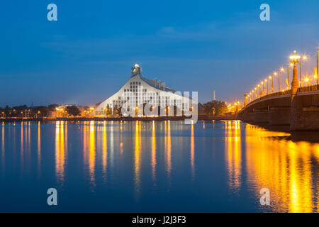 Lettische Nationalbibliothek und Stein Brücke über den Fluss Daugava in Riga. Beleuchtete Nachtaufnahme. Stockfoto