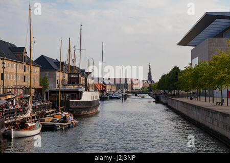 Menschen sind auf der Böschung des Kanals mit Booten mit Blick auf Oper entspannend. Kopenhagen, Dänemark. Stockfoto