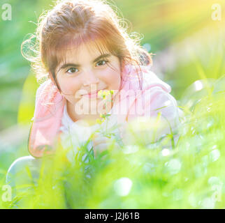 Porträt von einem niedlichen Baby-Mädchen genießen Blumen Duft, Spaß auf frischen grünen Wiese in sonniger Frühlingstag, kleines Kind mit Freude verbringen ti Stockfoto