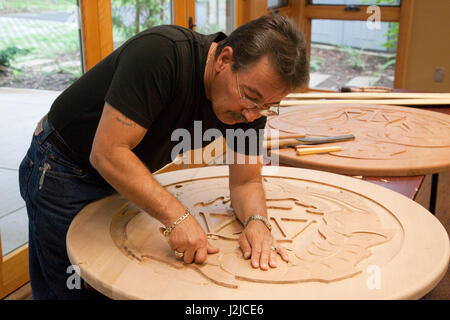 Küsten-Salish Schnitzer zeigt seine Kunstfertigkeit während schnitzen eine große traditionelle Zeder Holz Scheibe im Hilbub Kulturzentrum und Museum befindet sich im Tulalip Stämme Reservat in Marysville, WA Stockfoto