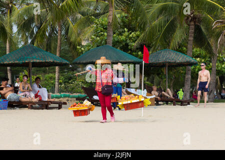 Sanya, China trägt 23. April 2017 - eine Frau-Verkäufer auf den Schultern eine Bar mit Körben voller Obst entlang des Strandes das Südchinesische Meer in Sanya Stockfoto