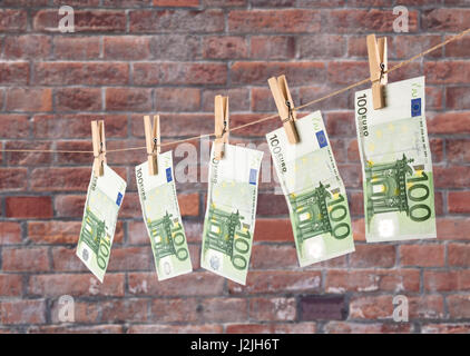 100 Euro-Banknoten, hängen, Wäscheleine auf Brick Wand Hintergrund. Geldwäsche Konzept Geld Stockfoto