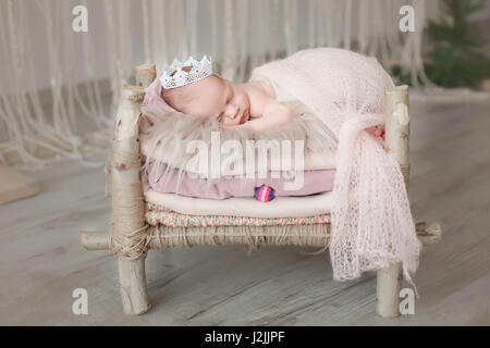 Neugeborenes Babymädchen schläft in einem Bett aus Holz. Die Prinzessin auf der Erbse. Stockfoto