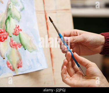 Mädchen malt Stillleben in Aquarell Kunstschule. Der Lehrer hilft, die Mängel im Bild korrigieren. Nahaufnahme der Hände. Kurse der Zeichnung für Erwachsene Stockfoto