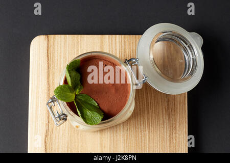 Tiramisu mit Minze in einem Glas auf einem rustikalen Holztisch Stockfoto