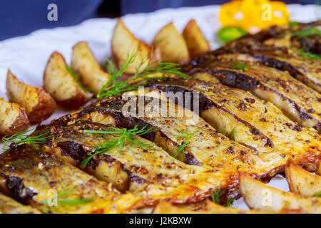 Ofen gebacken gegrillter Fisch mit Bratkartoffeln und Gemüse auf dem Teller Stockfoto