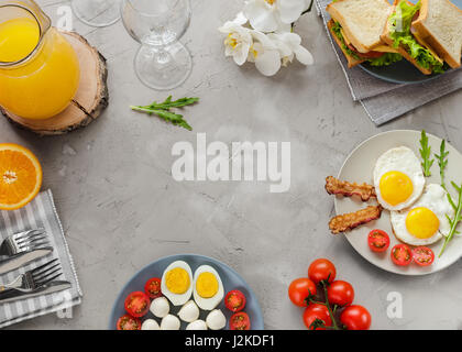 Frühstückstisch mit Spiegelei, Speck, Kirschtomaten, Gusto, Orangensaft Stockfoto