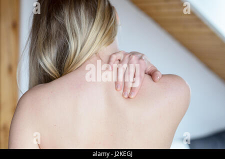 Rückansicht der Oberkörper der jungen Frau, die schmerzende Schulter mit der Hand reiben Stockfoto