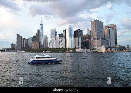 Eine Yacht, vorbei an Lower Manhattan in der Upper Bay, New York, Vereinigte Staaten Stockfoto