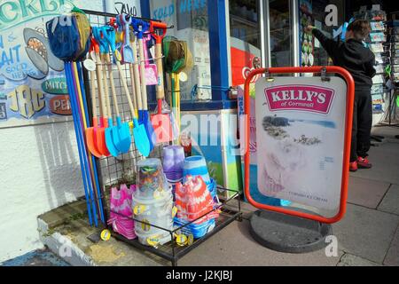 Newquay, Cornwall, UK - 1. April 2017: Childrens Eimer, Spaten und Fischernetze auf Verkauf außerhalb einen Strand einkaufen, während ein kleiner Junge Kellys Eis c wählt Stockfoto