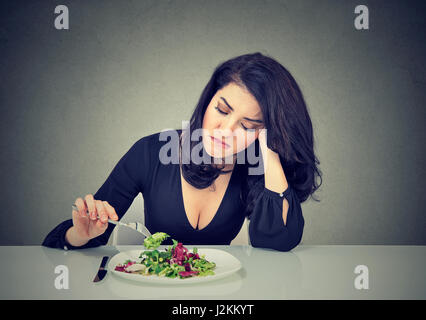 Junge Frau Essen grünen Blattsalat müde Diätbeschränkungen unzufrieden Stockfoto