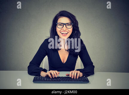 Lächelnde Frau auf einer Computertastatur tippen erstaunt Stockfoto