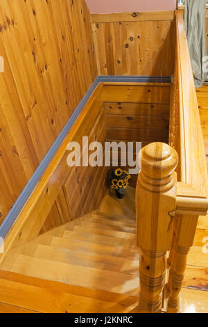 Kiefer und Ahorn Holztreppe führt zu dem unten Boden im Inneren eines Blockhauses Canadiana Cottage Stil Stockfoto
