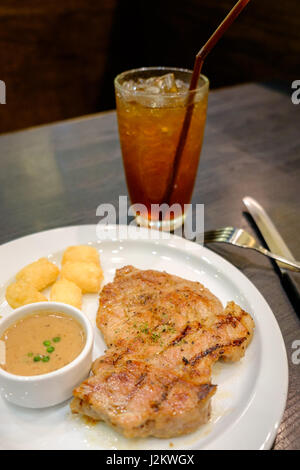 Schweineschnitzel mit Pfeffersauce mit Rösti Kartoffel auf weißen Teller serviert Stockfoto