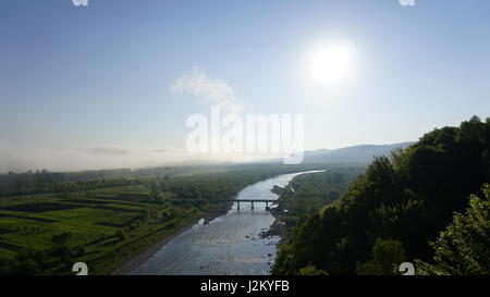 Schönen sonnigen Tallandschaft mit Breite Gebirgsbach zwischen den grünen Bäumen unter blauem Himmel Stockfoto