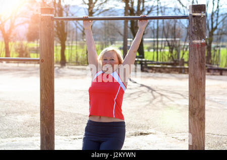 Beautiful senior Woman arbeiten auf einer horizontalen Leiste in einer ländlichen Sportarena in ein Fitness und gesunde Lebensweise-Konzept Stockfoto