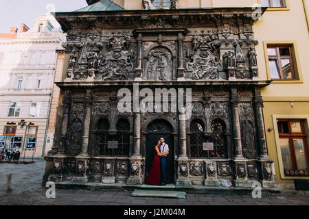 Schöne luxuriöse stilvolle Paar posieren auf einem Hintergrund von Lemberg romanische Kathedrale mit wunderbaren Basrelief Stockfoto