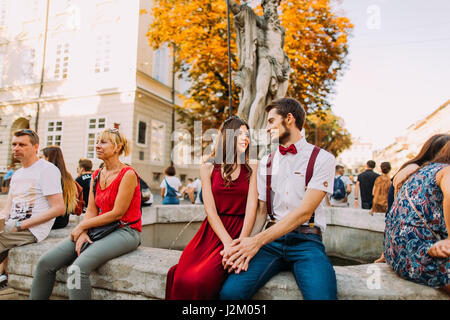 Zärtlich junges Paar sitzt auf dem alten Vintage Brunnen in Lviv Stadtzentrum Stockfoto