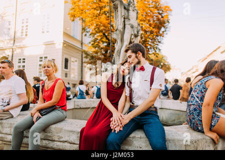 Zärtlich junges Paar sitzt auf dem alten Vintage Brunnen in Lviv Stadtzentrum Stockfoto
