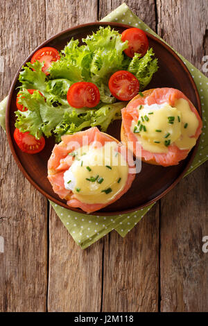 herzhaftes Frühstück: pochierten Eiern mit Lachs und Sauce Hollandaise auf eine Platte Nahaufnahme. Vertikale Ansicht von oben Stockfoto