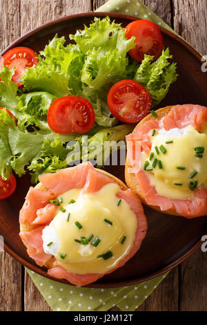 Eggs Benedict mit Lachs und Sauce Hollandaise auf eine Platte Nahaufnahme. Vertikale Ansicht von oben Stockfoto